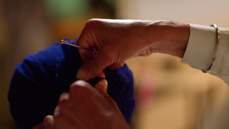 Close-Up-Studio-Shot-Of-Senior-Sikh-Man-Helping-Younger-Sikh-Man-To-Tie-Fabric-For-Turban-Against-Plain-Background-Shot-In-Real-Time-2